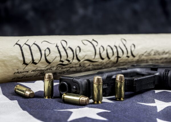 A handgun with bullets symbolizing gun rights while framed against the United States constitution.